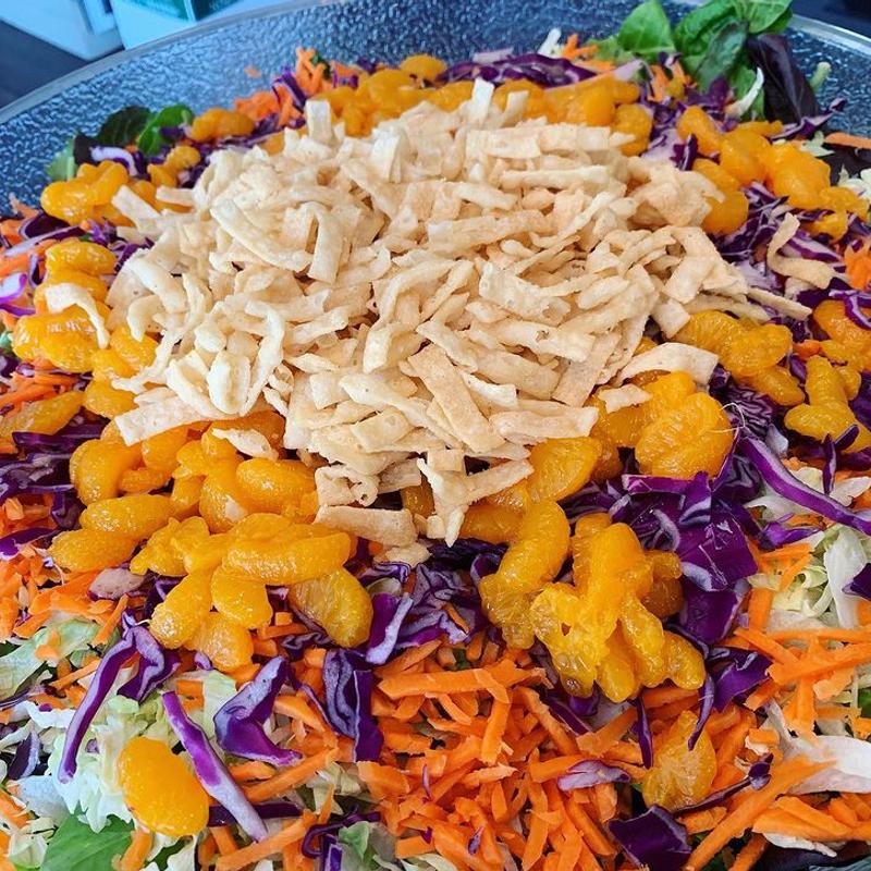 A wide serving platter of shredded salad — red cabbage, carrot, mandarin segments and crisp noodles piled in the centre.